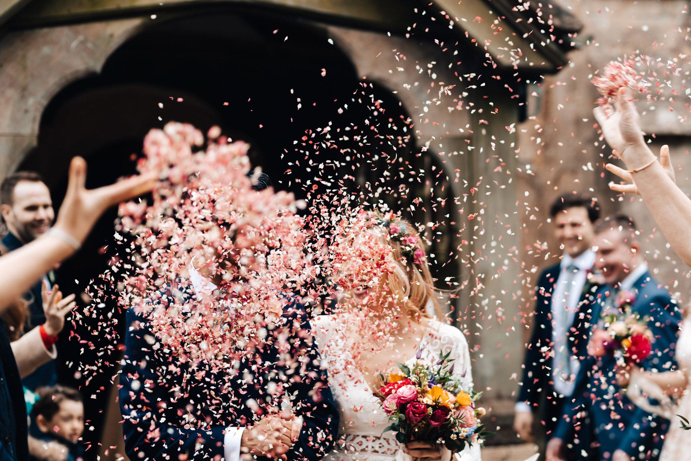 Confetti explosion obscures the whole of the newlywed bride and grooms faces making it appear as if they have confetti for faces