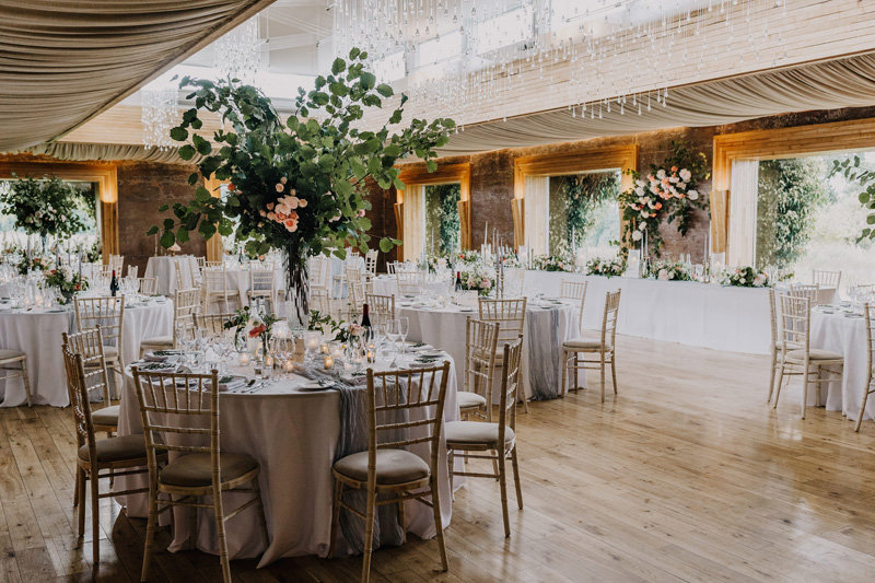 Round tables with tall floral centrepieces in The Gillyflower at Elmore Court