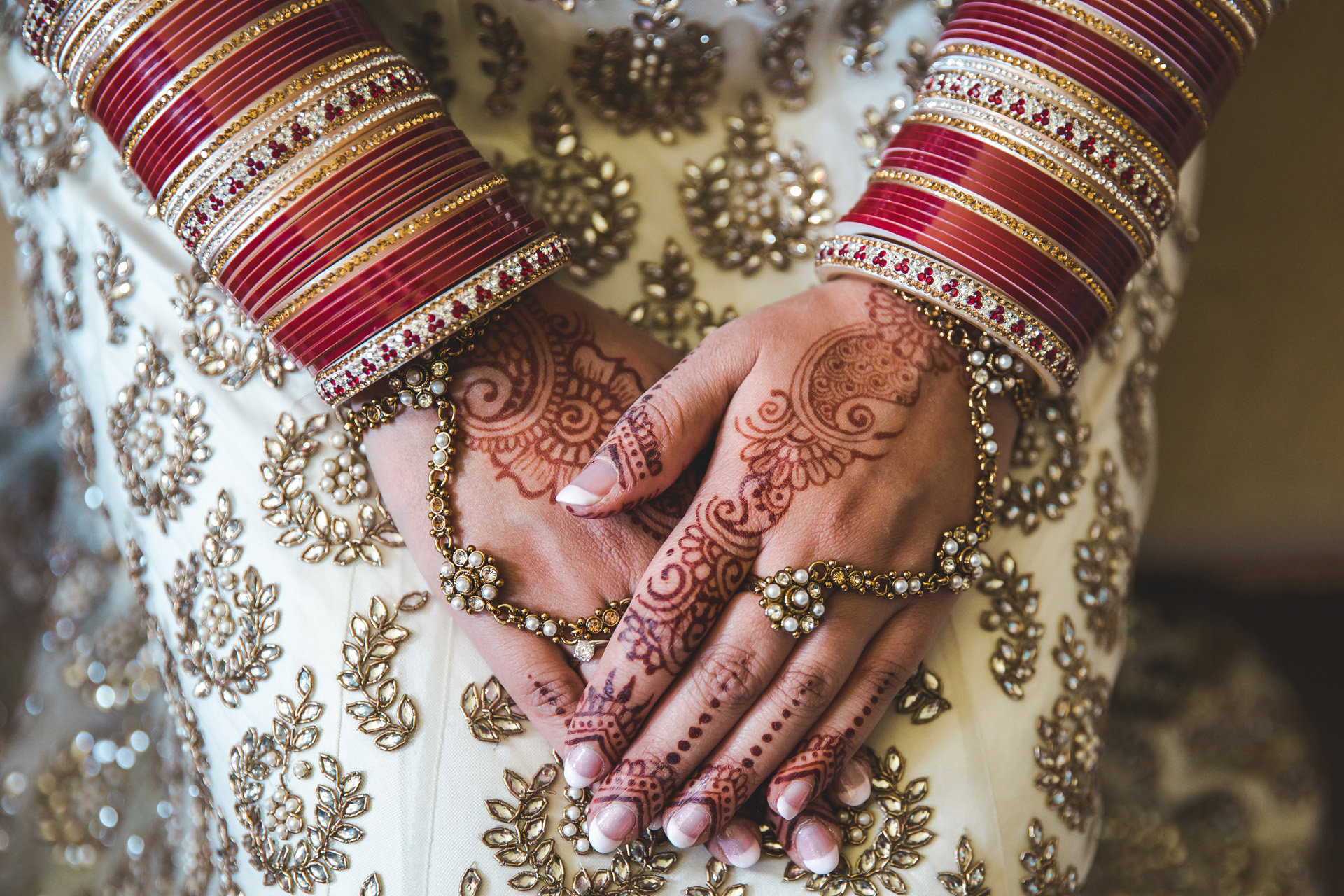 Mehndi on brides hands with red bangles for a beautiful indian wedding in the cotswolds