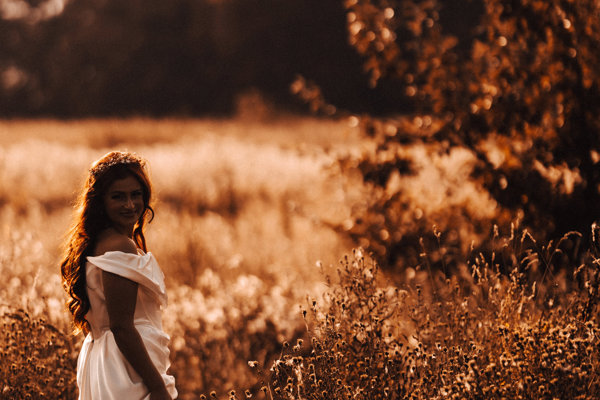 Glowing golden hour bride walking the fields in September sunshine