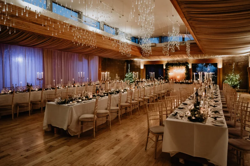 three long wedding reception tables in the Gillyflower at Elmore Court, all candle lit and elegantly decorated