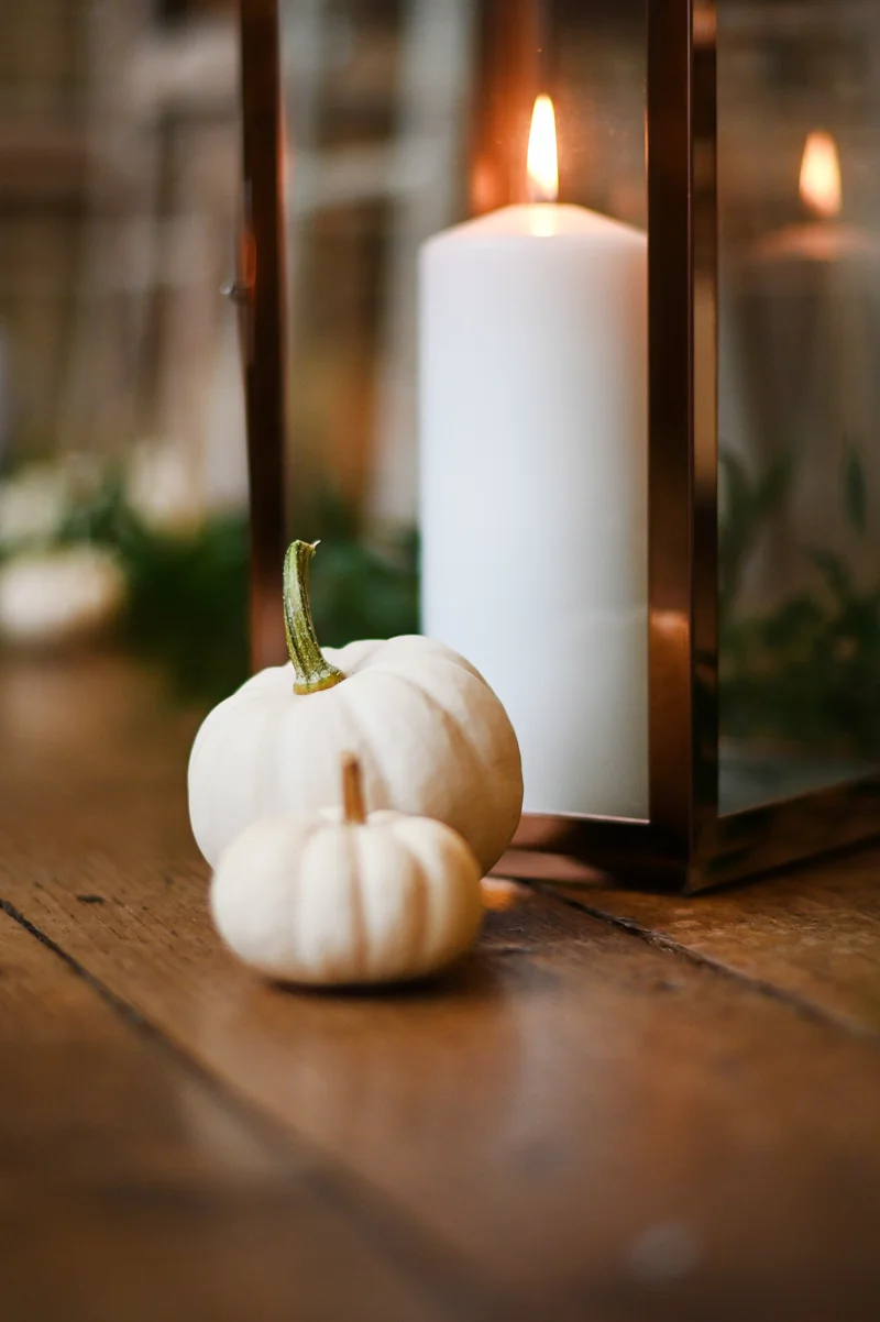 White pumpkins and lanterns with candles decorate the aisle for this hocus pocus themed halloween wedding