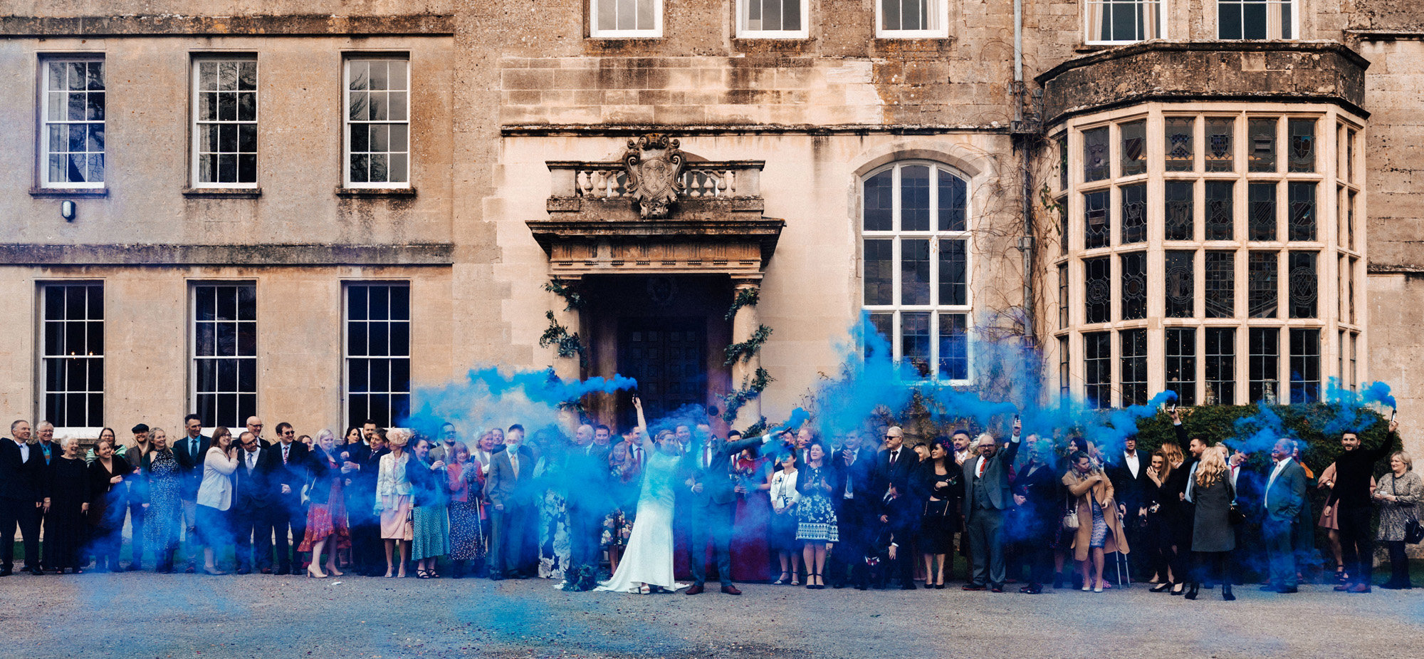 Blue smoke bombs for a surprise gender reveal at this winter wedding with pregnant bride at stately home in the cotswolds