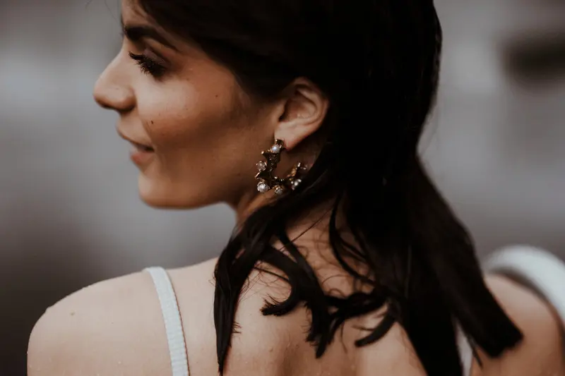 Beautiful Italian bride with wet hair from wild swimming wearing gold circle earrings dotted with pearls
