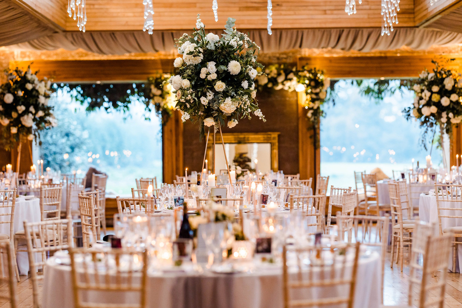 romantic White roses and greenery in spheres reminiscent of alice in wonderland rose bushes at wedding reception in the cotswolds