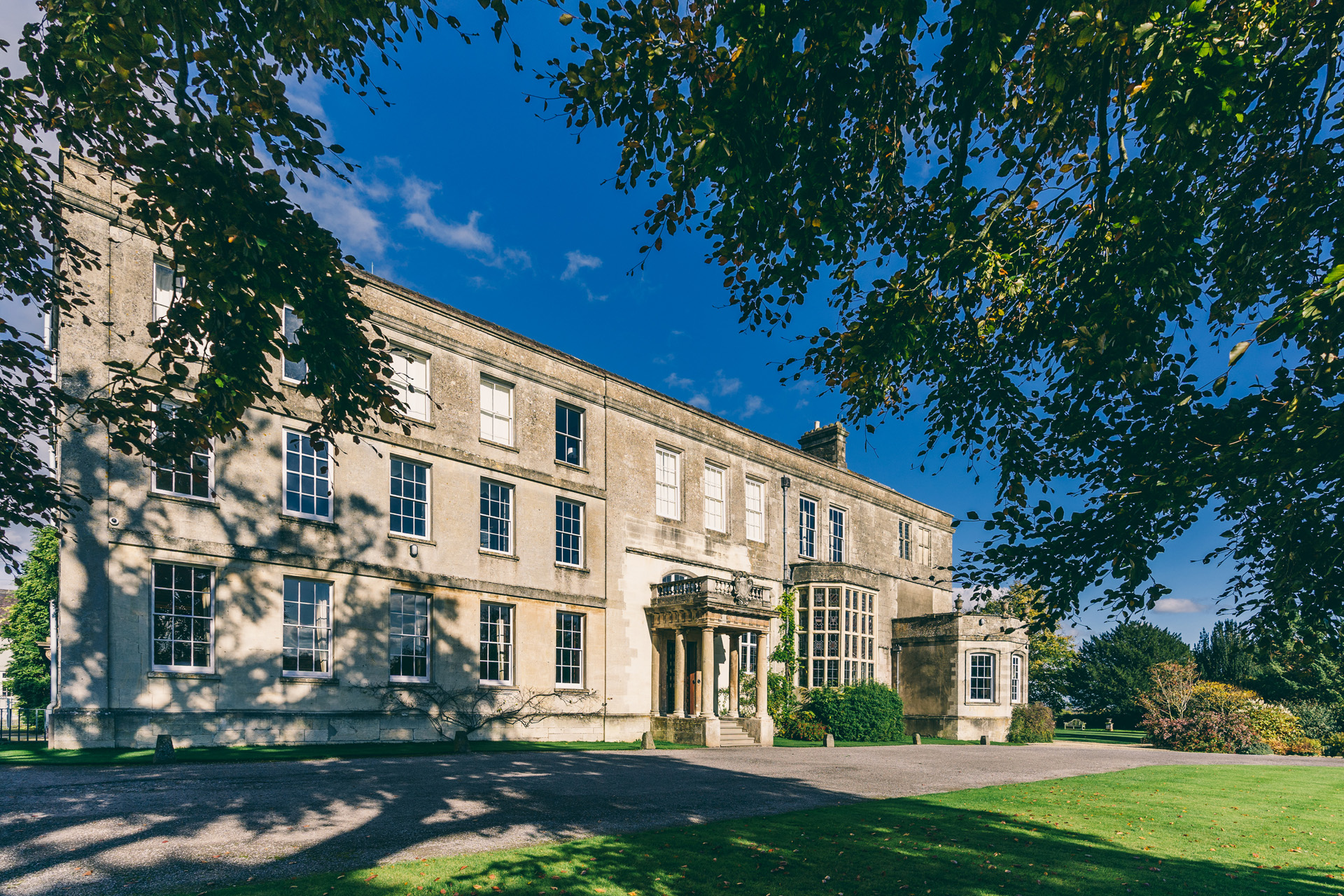 Mansion house elmore court framed by copper beech against deep blue sky. Pop up covid safe events are happening throughout December 2020 to keep this old house happy