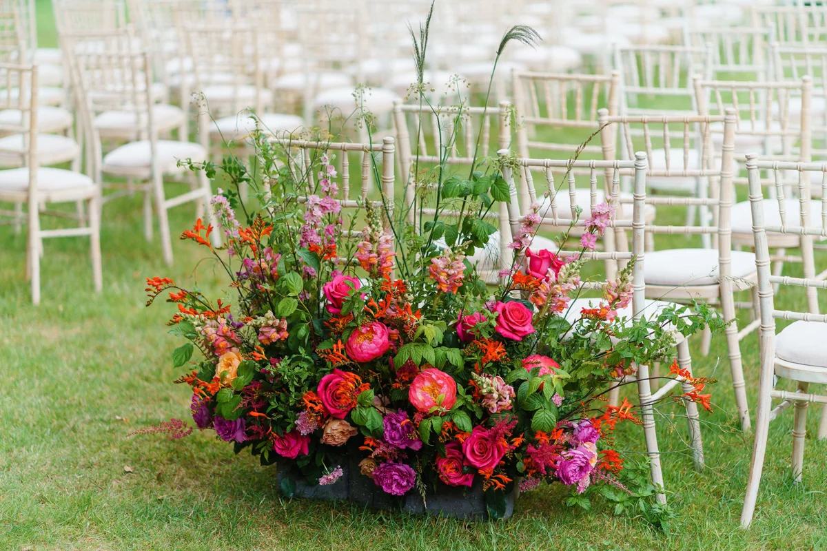 Pink and red flowers at an outdoor wedding ceremony on lovely green grass