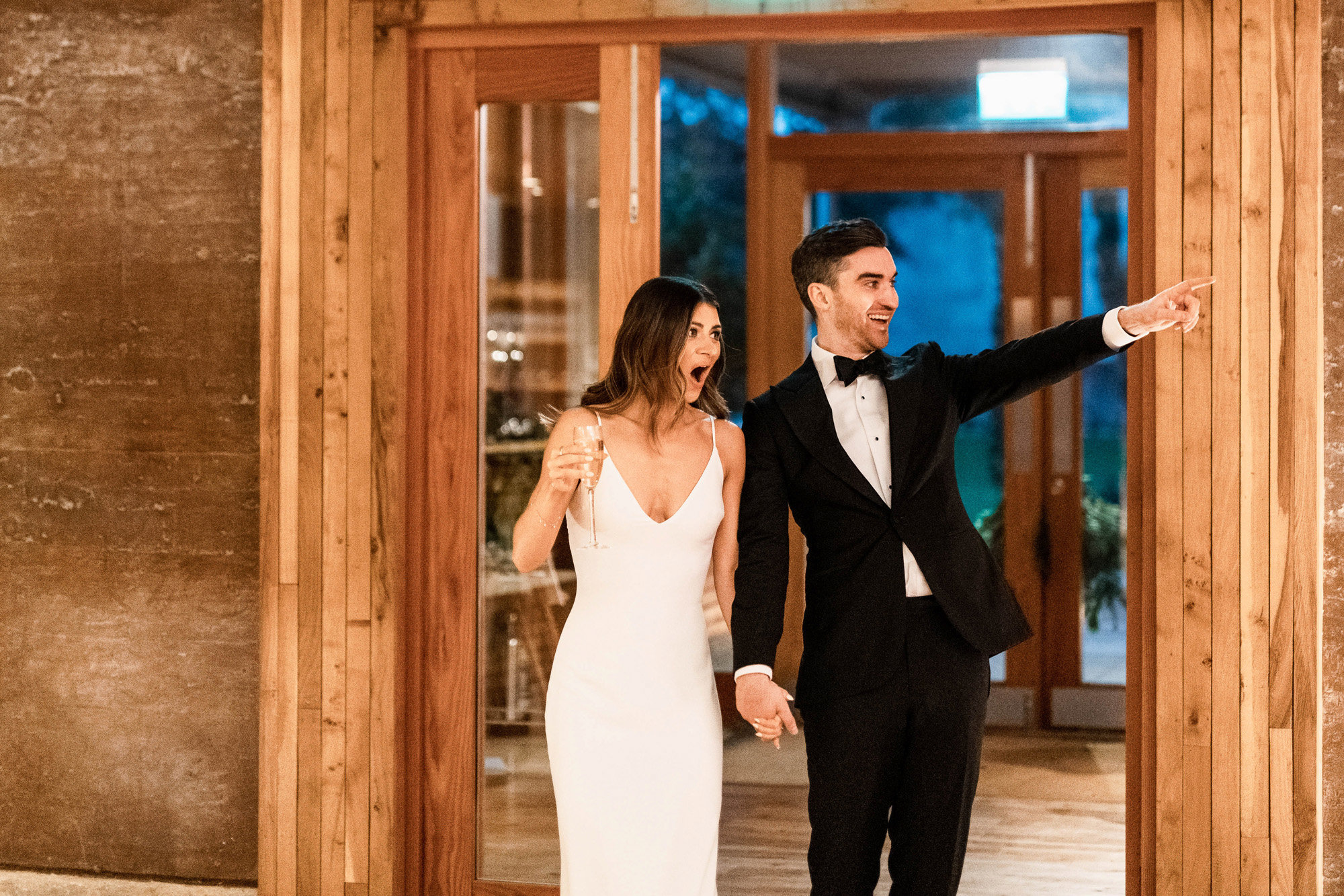 Black tie bride and groom walking into their party wedding reception