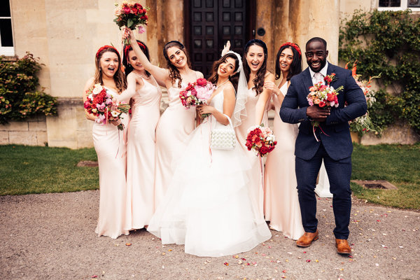 Wedding party. with Bridesmaids and bridesman pose outside stately home Elmore Court at a beautiful bright pink and red Persian wedding