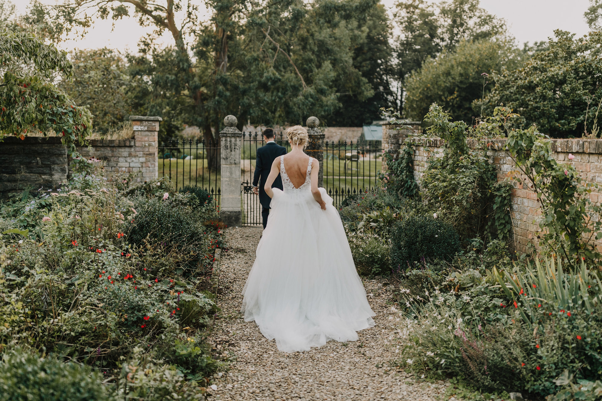 Bride and groom walking towards the walled garden on their wedding day at manor house elmore court