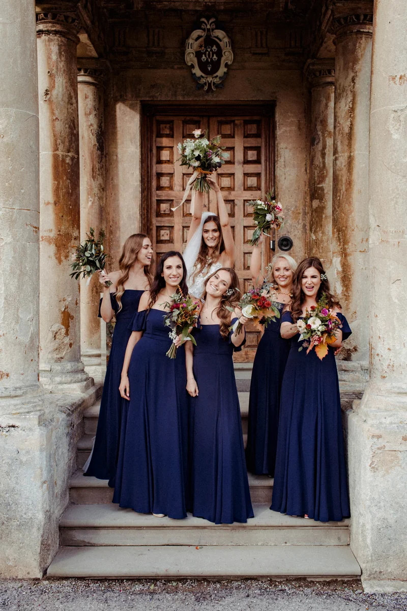 Bridal party on steps of mansion house wedding venue holding autumnal bouquets
