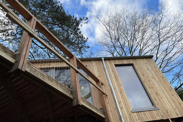 Woodland treehouse against a beautiful blue sky with trees in the background