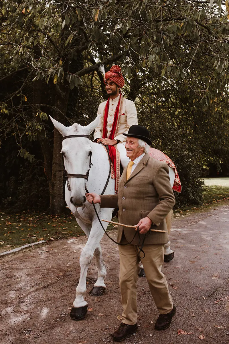 Indian groom arrives on horse back as part of the baraat procession and party at indian wedding venue