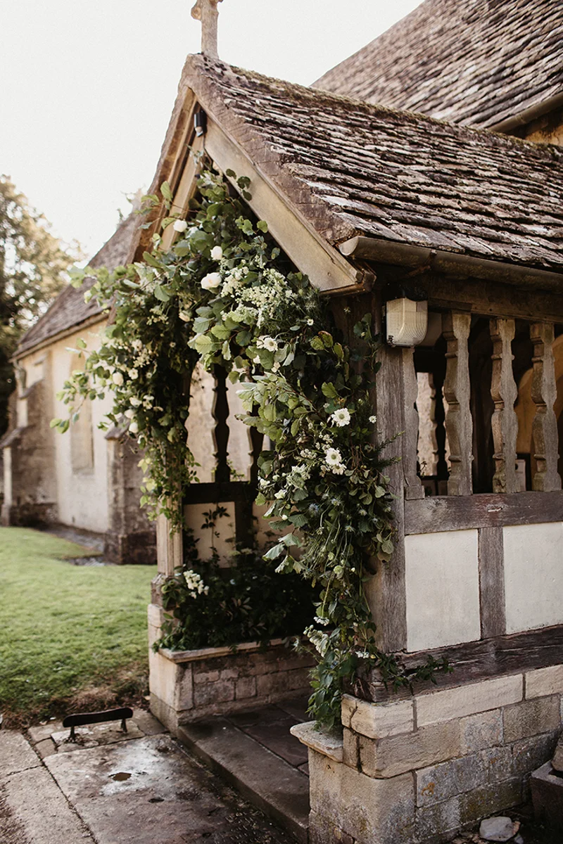 The prettiest church in England entrance decorated with greenery for a wedding at Elmore