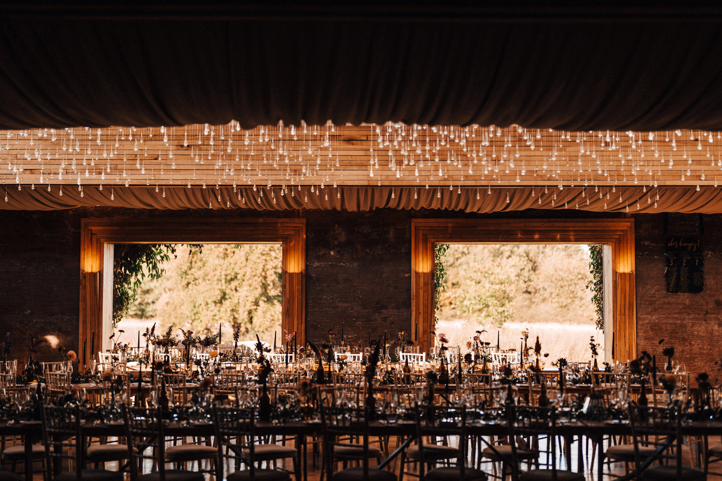 October wedding reception with dark details in a magical and twinkly sustainable reception venue in the cotswolds