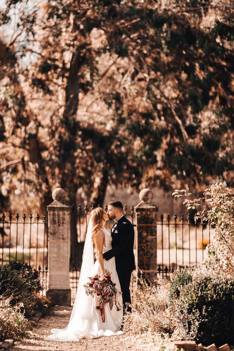 Newlywed couple kiss in autumn walled gardens of Gloucestershire wedding venue elmroe court