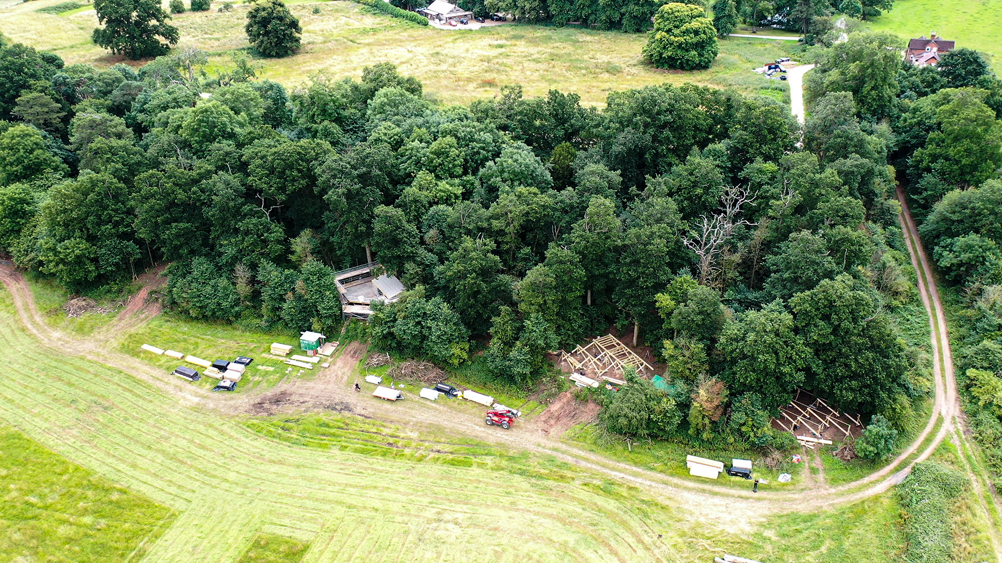 Ariel view of three treehouses being constructed on the border of a woodland which overlooks a stunning field