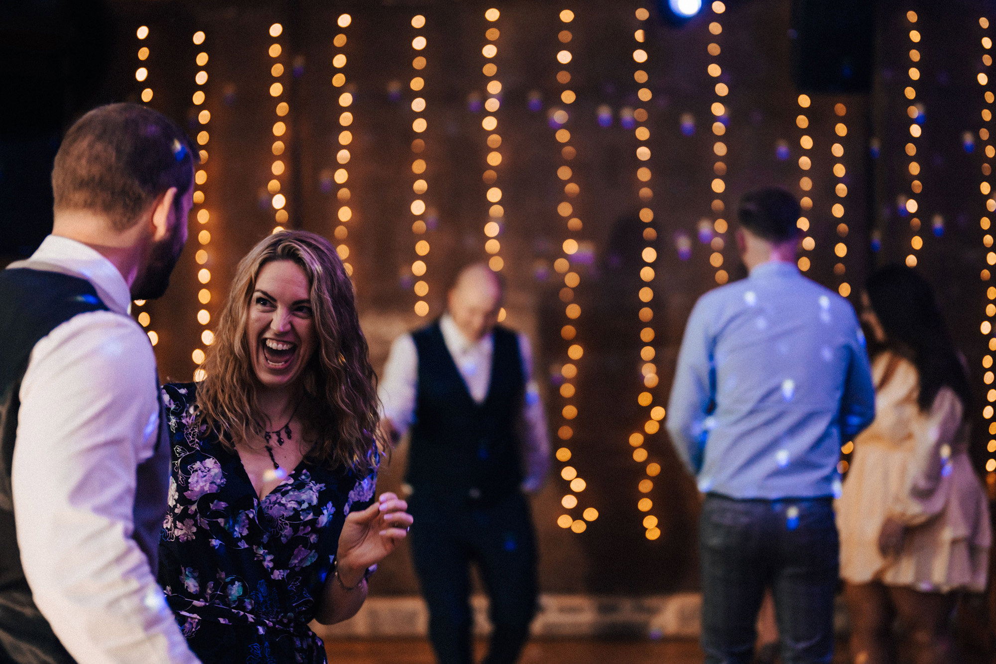 Guests having fun dancing at a magical party wedding with twinkling lights and candles in October