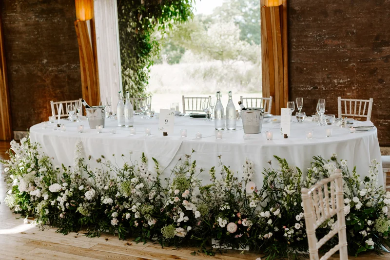 wild meadow style wedding flowers around the bottom of the top table at a wild wedding at elmore court