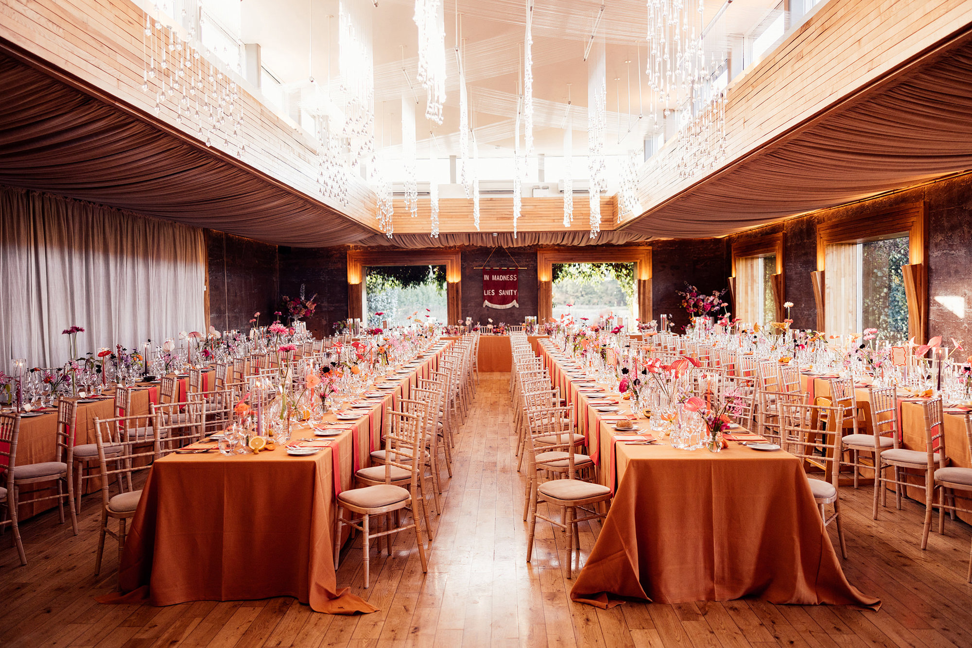 Colourful wedding reception idea Orange tables with bright flowers at eco venue in the cotswolds