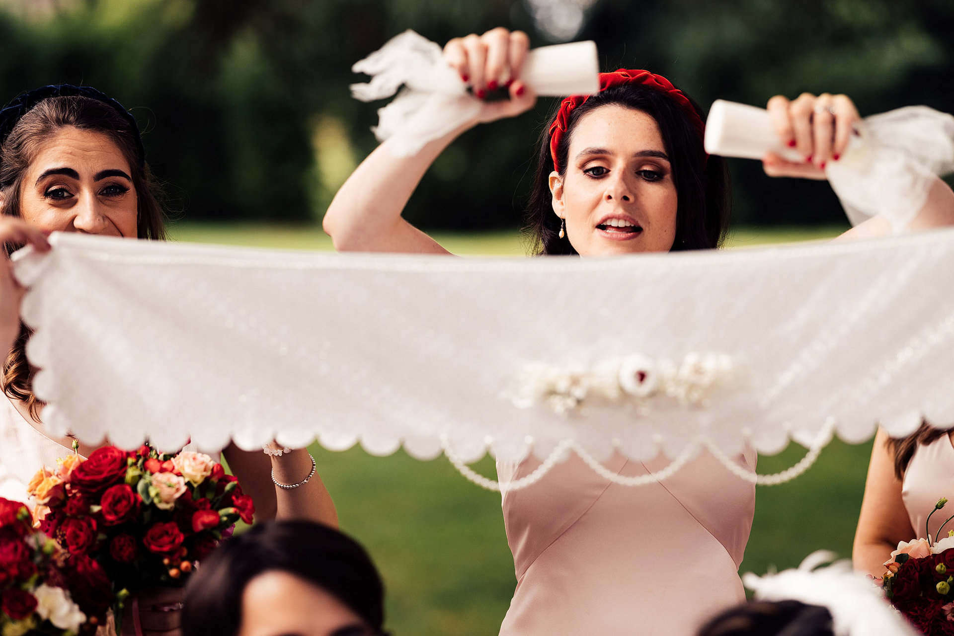 Bridesmaid sprinkles sugar onto silk veil at persian ceremony outside stately home elmore court in the cotswolds