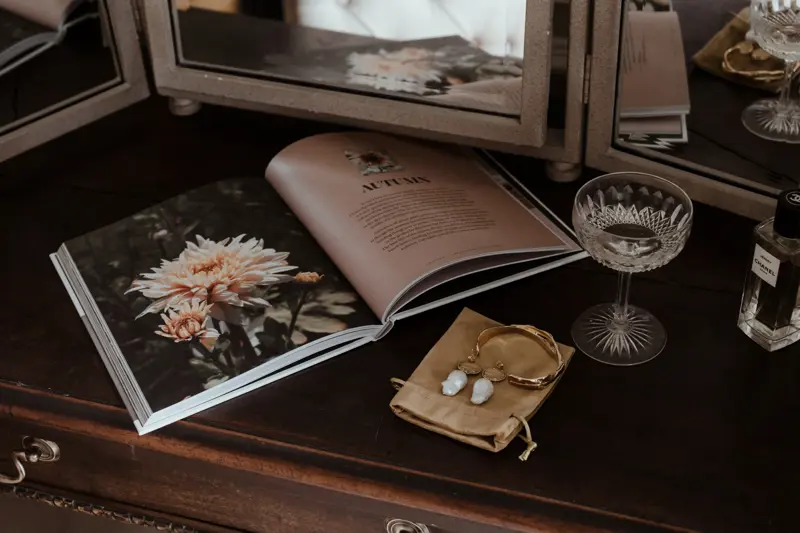 Eco wedding shoot with wild flower magazine and pearl earrings and champagne glass laid out on dressing table
