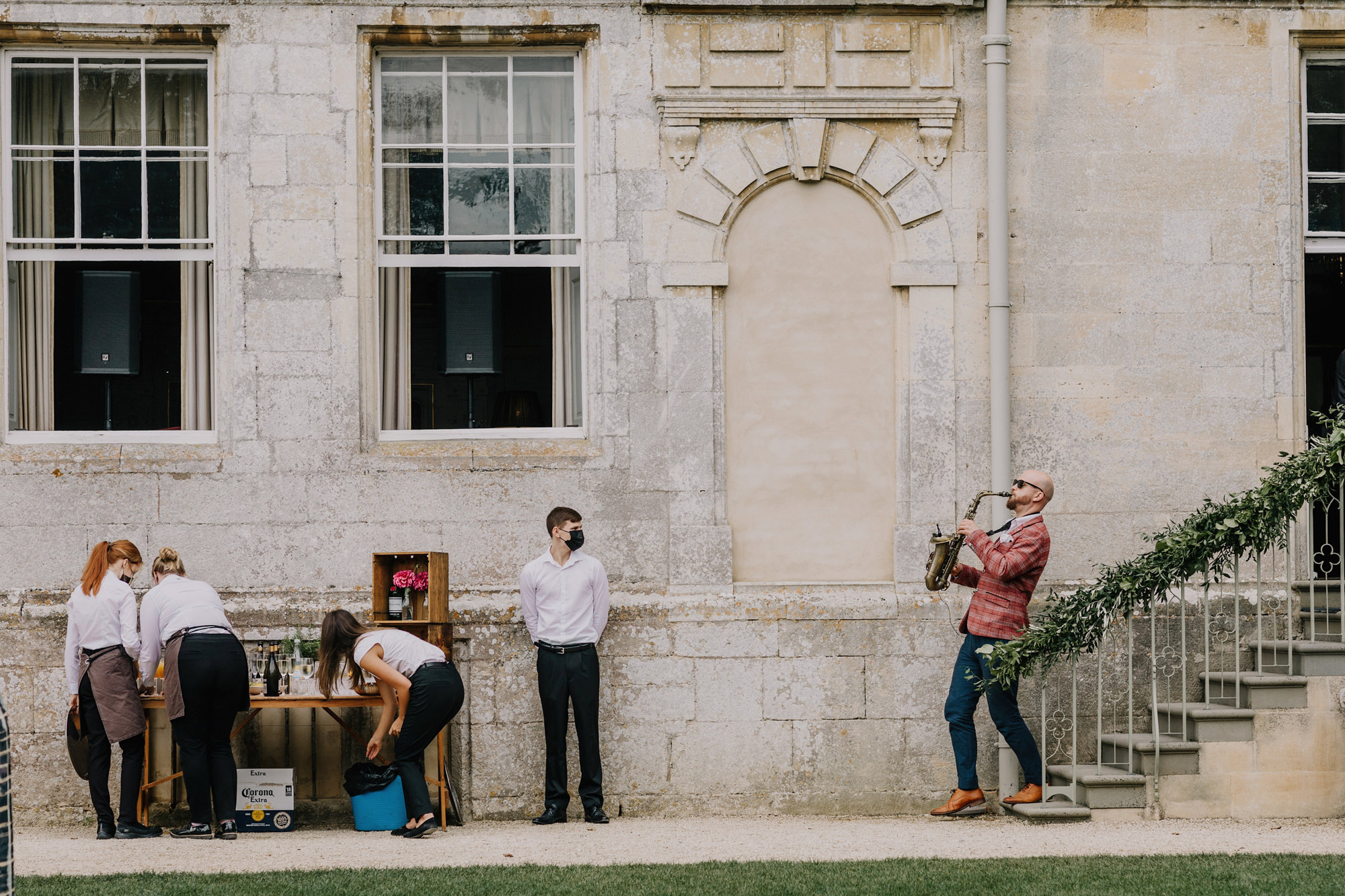 Walkabout musician plays the saxophone down the steps as a surprise festival addition to outdoor wedding