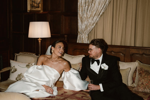 Luxe bride and groom on huge stately home bed at their luxury wedding venue in the cotswolds