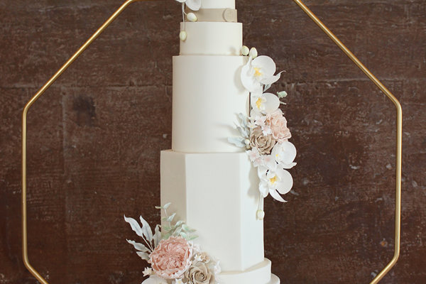Extra tall 5 tier luxury modern wedding cake with white icing and different shaped layers decorated with pale pink and white flowers at elmore court