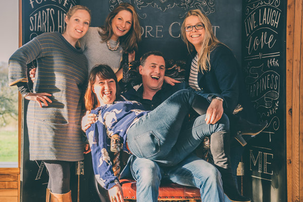 Anselm Guise with Team E member on lap laughing at Elmore Court wedding fair in Gloucestershire