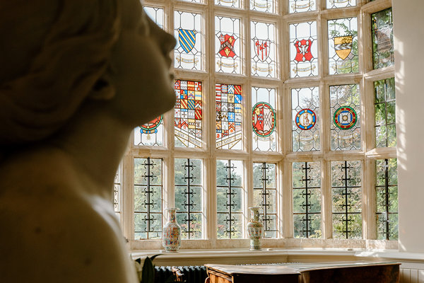 Luxurious wedding photography of a stately home wedding venue with stained glass windows and marble statues