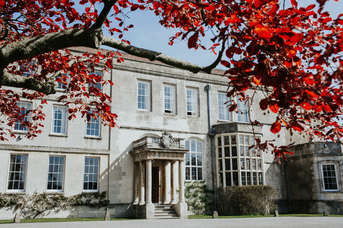 Bright red beech tree leaves frame stately home Elmore Court