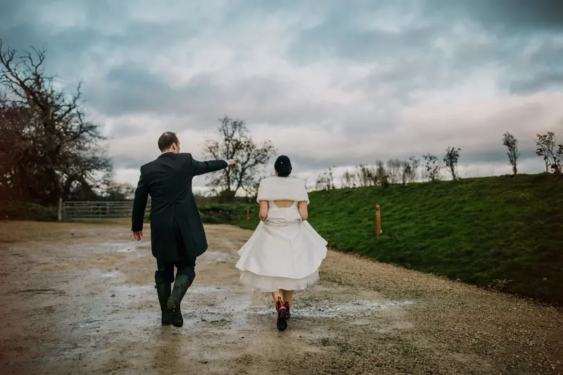 Bride wearing wellies and shawl on a rainy day