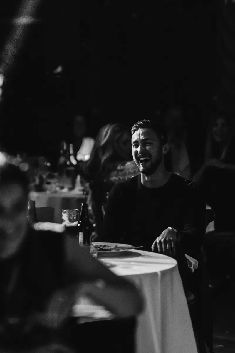 Guests roaring with laughter sitting at round tables at cabaret dinner the parrot cage