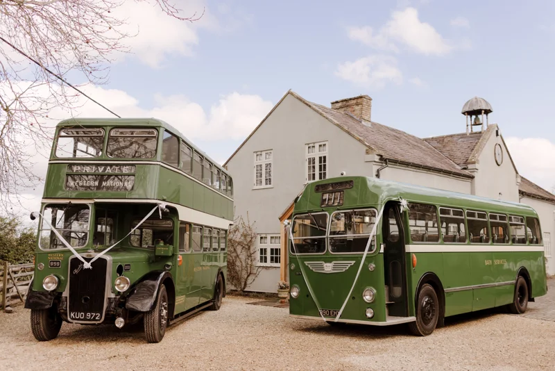 Vintage buses parked in front of the coach house at elmore court for a garden wedding