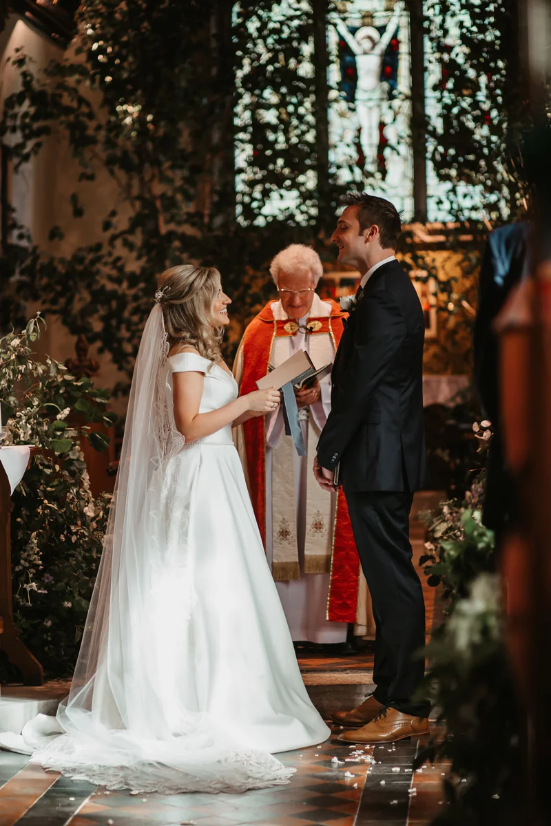 Religious ceremony in church Vicar behind couple who are smiling holding hands in church
