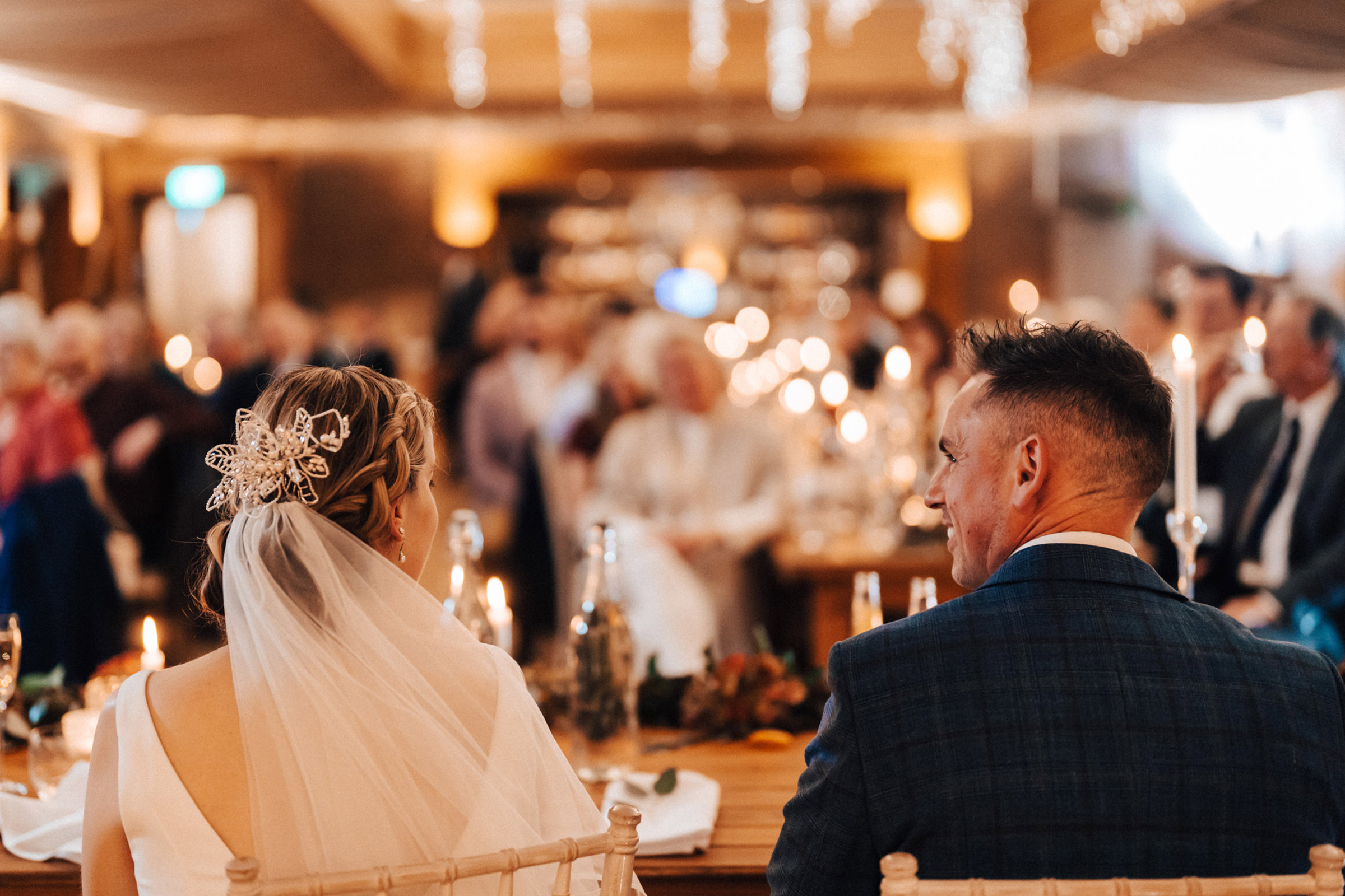 bride and groom sitting at their Christmas wedding reception with hundreds of candles in Gloucestershire UK