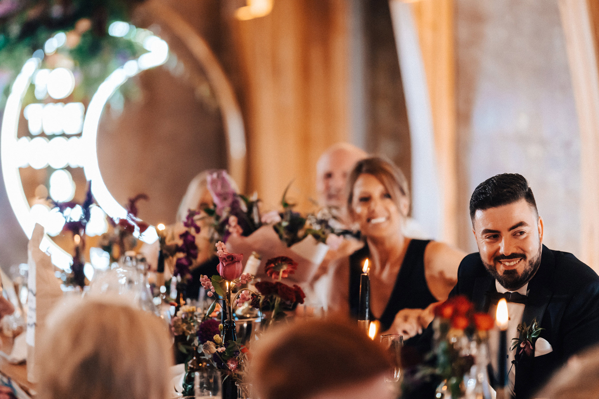 Guests and groom in black happily smiling at Magical wedding reception venue with celestial decor