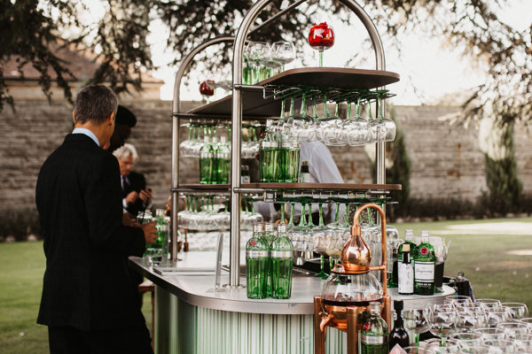 Outdoor gin bar in beautiful green ombre with copper details stationed under the cedar tree for a cool outdoor wedding reception at Elmore Court