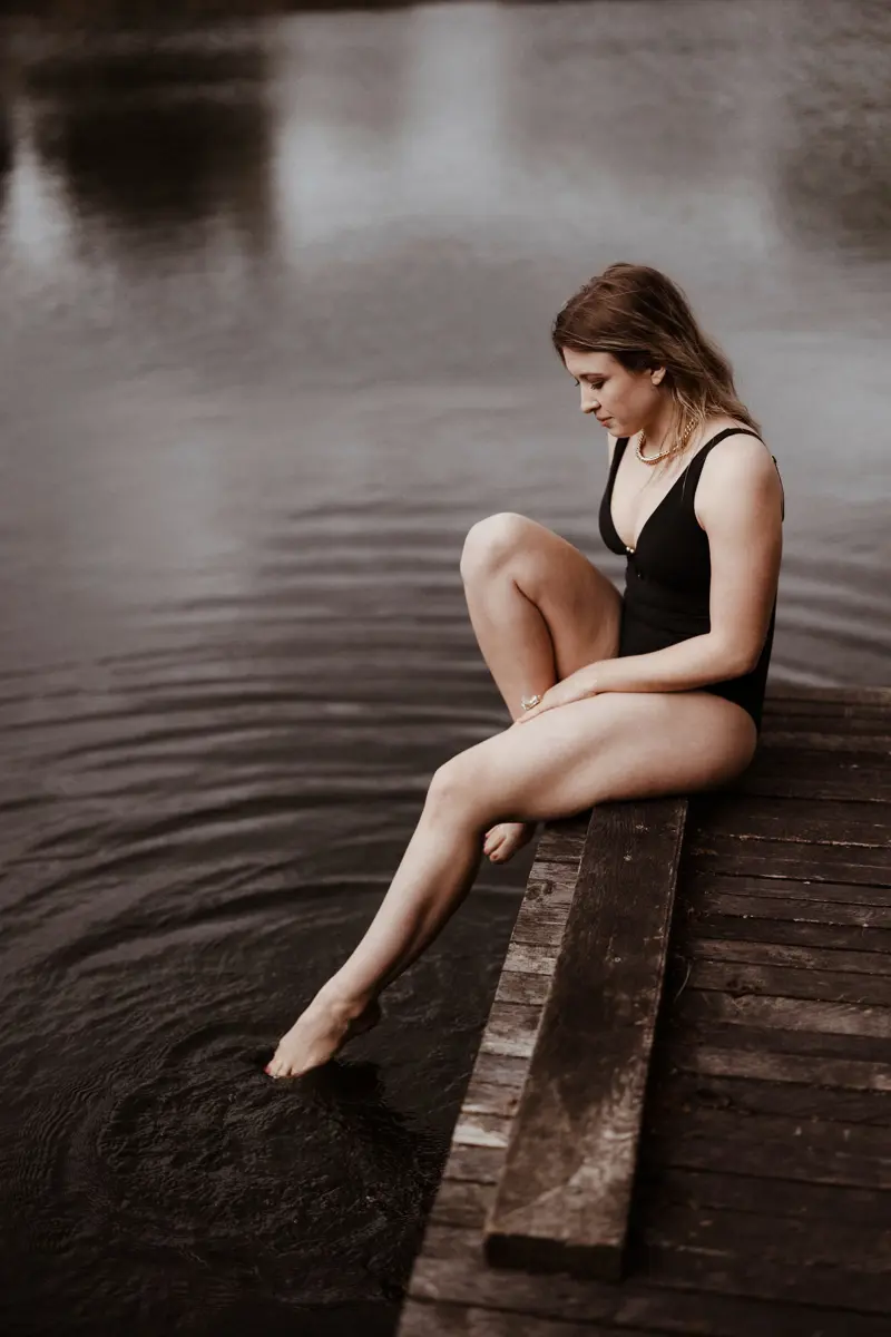 wild bride swims in open water on wedding day dipping her toe in the lake testing water before diving in