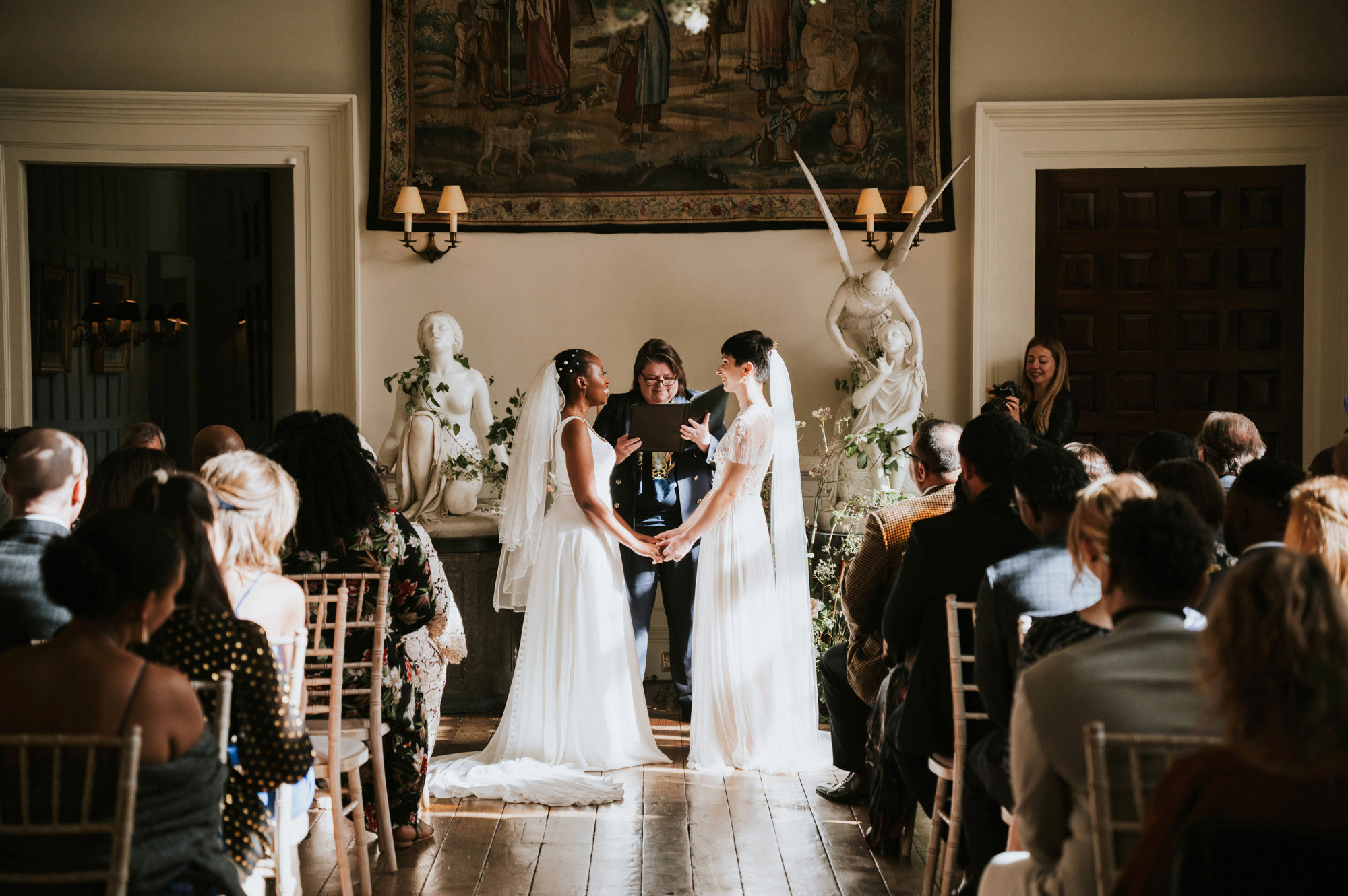 Two brides look ethereal in white wedding dresses and veils in Magical same sex wedding ceremony in beautiful stately home hall