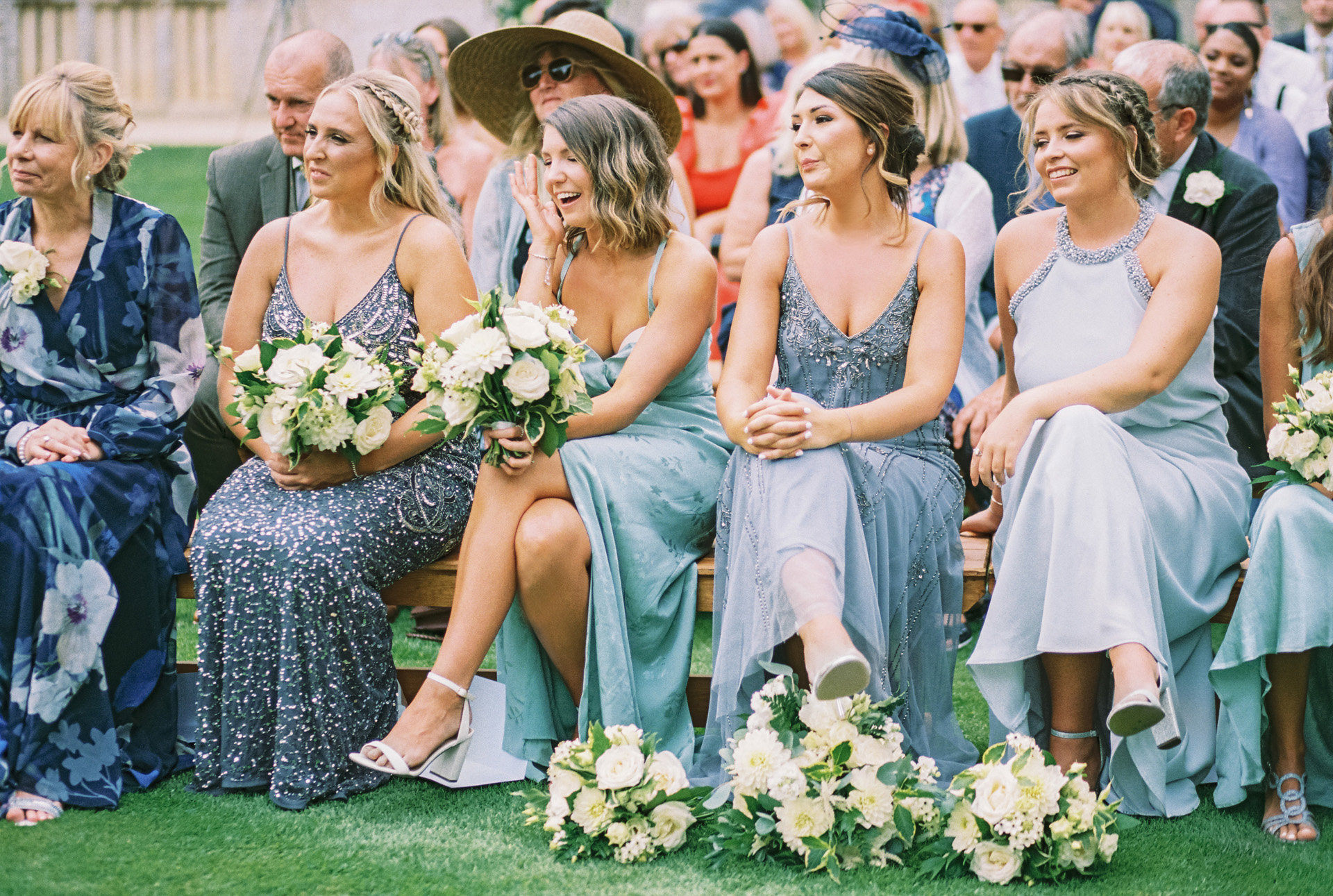 Outdoor wedding inspiration mismatched green hue bridesmaids sit and watch the outdoor ceremony