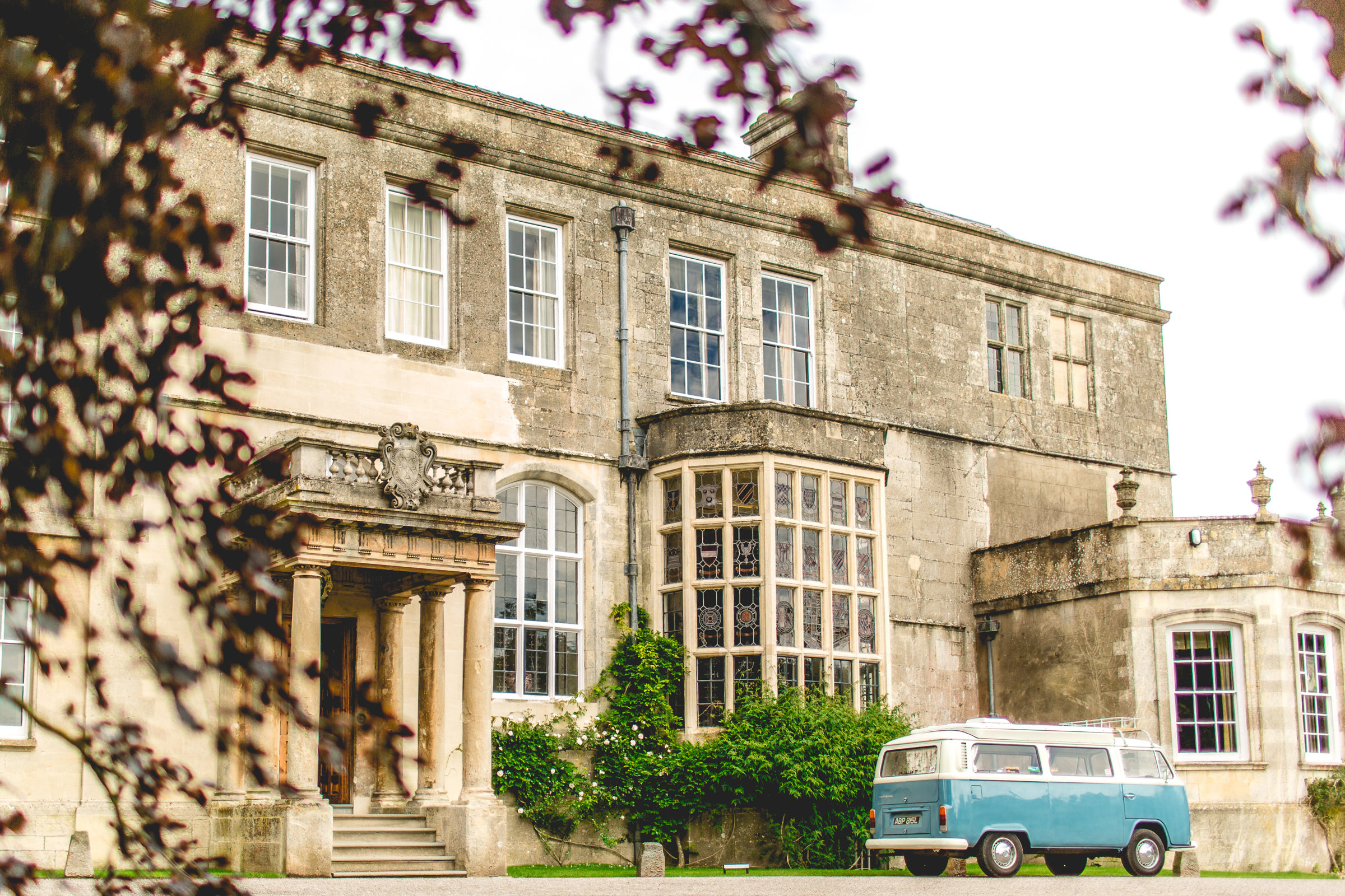 Stately home Elmore Court with a blue VW camper parked outside and copper beech in front of the house at a wedding