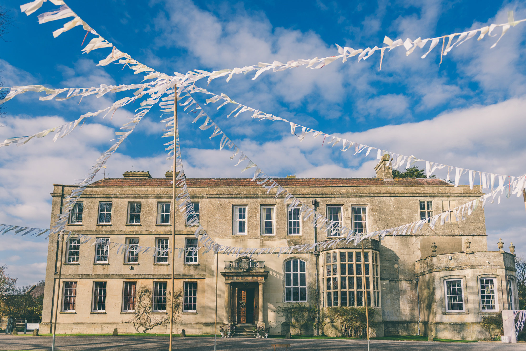 Bunting on poles outside the front of mansion house elmore court for a jubilee tea party inspired garden wedding