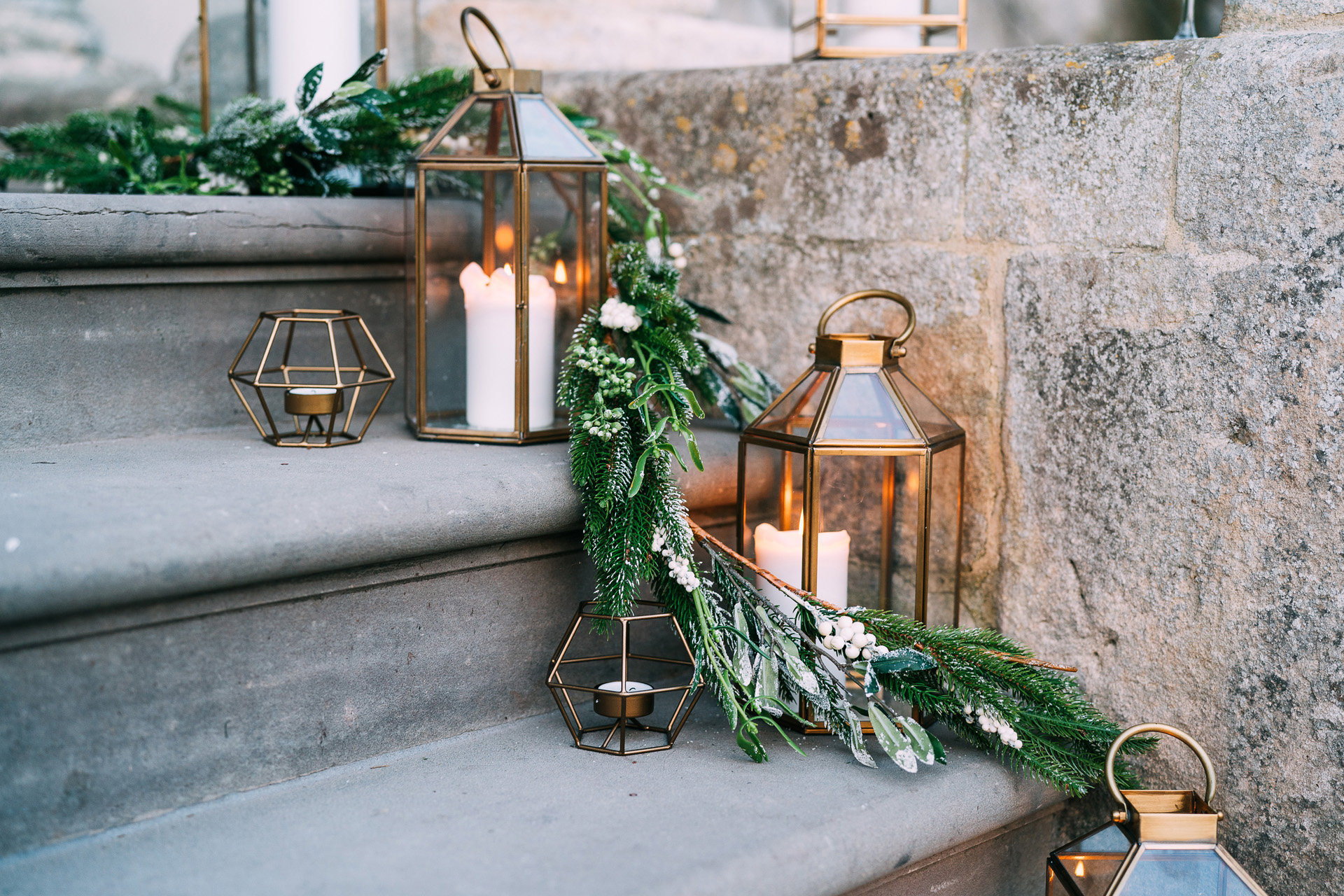 Christmas lanterns with green foliage decorating the steps of wedding venue for a Christmas wedding